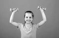 Cute little girl doing exercises with dumbbells in yellow background. Closeup portrait of sporty child with dumbbells Royalty Free Stock Photo