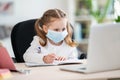 Cute little girl, doing homework, writing in notebook, using laptop, e-learning Royalty Free Stock Photo