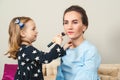 Cute little girl doing makeup to her mom. Young beautiful mother and little daughter while applying makeup. Mom and child girl Royalty Free Stock Photo