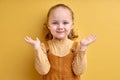 Cute little girl doubting and shrugging shoulders in questioning gesture, isolated