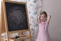 Little Preschool Girl Writing on Blackboard. Toddler girl holding chalk and drawing. Royalty Free Stock Photo