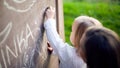 Cute little girl drawing on blackboard. Toddler girl holding chalk and drawing. Royalty Free Stock Photo