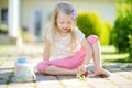 Cute little girl drawing with colorful chalks on a sidewalk. Summer activity for small kids. Royalty Free Stock Photo