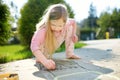 Cute little girl drawing with colorful chalks on a sidewalk. Summer activity for small kids Royalty Free Stock Photo