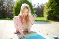 Cute little girl drawing with colorful chalks on a sidewalk. Summer activity for small kids Royalty Free Stock Photo