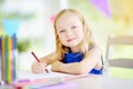 Cute little girl drawing with colorful pencils at a daycare. Creative kid painting at school