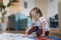 Cute little girl drawing with crayons, sitting on the floor at home. Royalty Free Stock Photo