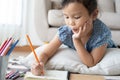 Cute little girl drawing homework and writing with pen on paper in her home Royalty Free Stock Photo