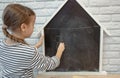 Cute little girl draws with chalk on the blackboard Royalty Free Stock Photo