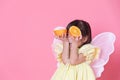 Cute little girl dress up as a angel with white wings holding a half of orange Royalty Free Stock Photo