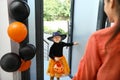 Cute little girl dressed as witch trick-or-treating at doorway