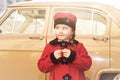 Cute little girl dressed in retro coat posing near oldtimer car Royalty Free Stock Photo