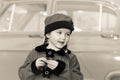 Cute little girl dressed in retro coat posing near oldtimer car Royalty Free Stock Photo