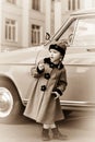 Cute little girl dressed in retro coat posing near oldtimer car Royalty Free Stock Photo