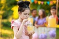 Cute little girl drinking natural lemonade in park. Summer refreshing beverage Royalty Free Stock Photo