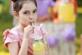 Cute little girl drinking natural lemonade in park, space for text. Summer refreshing beverage Royalty Free Stock Photo