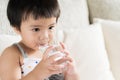 Cute little girl drinking water on sofa at home. Royalty Free Stock Photo