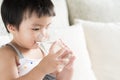 Cute little girl drinking water on sofa at home Royalty Free Stock Photo