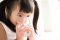 Cute little girl drinking water on sofa at home. Royalty Free Stock Photo