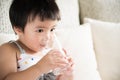 Cute little girl drinking water on sofa at home. Royalty Free Stock Photo