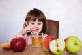 Cute little girl drinks apple juice using drinking straw. Baby girl with juice and fruit apples