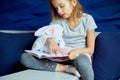 Cute little girl eading a book with stuffed teddy bunny toy