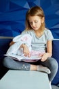 Cute little girl eading a book with stuffed teddy bunny toy Royalty Free Stock Photo