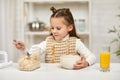 Cute little girl eating breakfast: cereal and orange juice Royalty Free Stock Photo