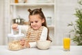 Cute little girl eating breakfast: cereal and orange juice Royalty Free Stock Photo