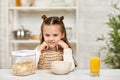 Cute little girl eating breakfast: cereal and orange juice Royalty Free Stock Photo