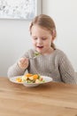 Cute little girl eating a fruit salad in design dining room. Child having a dinner at home. Healthy nutrition for small Royalty Free Stock Photo