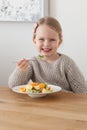Cute little girl eating a fruit salad in design dining room. Child having a dinner at home. Healthy nutrition for small Royalty Free Stock Photo