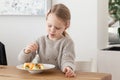 Cute little girl eating a fruit salad in design dining room. Child having a dinner at home. Healthy nutrition for small Royalty Free Stock Photo