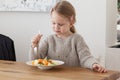 Cute little girl eating a fruit salad in design dining room. Child having a dinner at home. Healthy nutrition for small Royalty Free Stock Photo