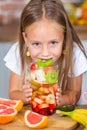 Cute little girl eating healthy fruit salad in the kitchen at home Cute little girl cooking in the kitchen. Healthy food concept. Royalty Free Stock Photo