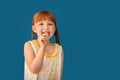 Cute little girl eating lollipop on color background Royalty Free Stock Photo