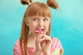 Cute little girl eating lollipop on color background Royalty Free Stock Photo