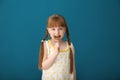 Cute little girl eating lollipop on color background Royalty Free Stock Photo