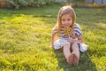 Cute little girl eating a lollipop on the grass in summertime.