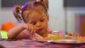 cute little girl eating a piece of cake on a paper plate with a plastic fork. Royalty Free Stock Photo