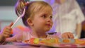 cute little girl eating a piece of cake on a paper plate with a plastic fork. Royalty Free Stock Photo