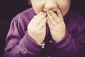 Cute little girl eating sweet macarons with the dirty finger