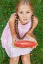 Cute little girl eating watermelon on the grass in summer time. with ponytail long hair and toothy smile sitting on grass and enjo Royalty Free Stock Photo