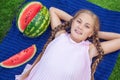 Cute little girl eating watermelon on the grass in summer time. with ponytail long hair and toothy smile sitting on grass and enjo Royalty Free Stock Photo