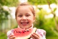 Cute little girl eating watermelon on the grass in summertime Royalty Free Stock Photo
