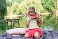 Cute little girl eating watermelon while sitting on a blanket by the lake Royalty Free Stock Photo