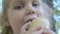 Cute little girl eats ice cream outside. Close-up portrait of blonde girl sitting on park bench and eating icecream Royalty Free Stock Photo