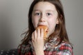 a cute little girl emotionally eating a hamburger, sandwich, cheeseburger or burger and smiling at home