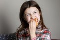 A cute little girl emotionally eating a hamburger, sandwich, cheeseburger or burger and smiling at home