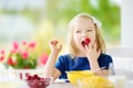 Cute little girl enjoying her breakfast at home. Pretty child eating corn flakes and raspberries and drinking milk before school. Royalty Free Stock Photo